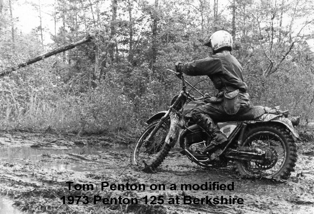 Motorcyclist rides through muddy forest trail.