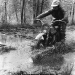 Rider on vintage Penton motorcycle through muddy terrain
