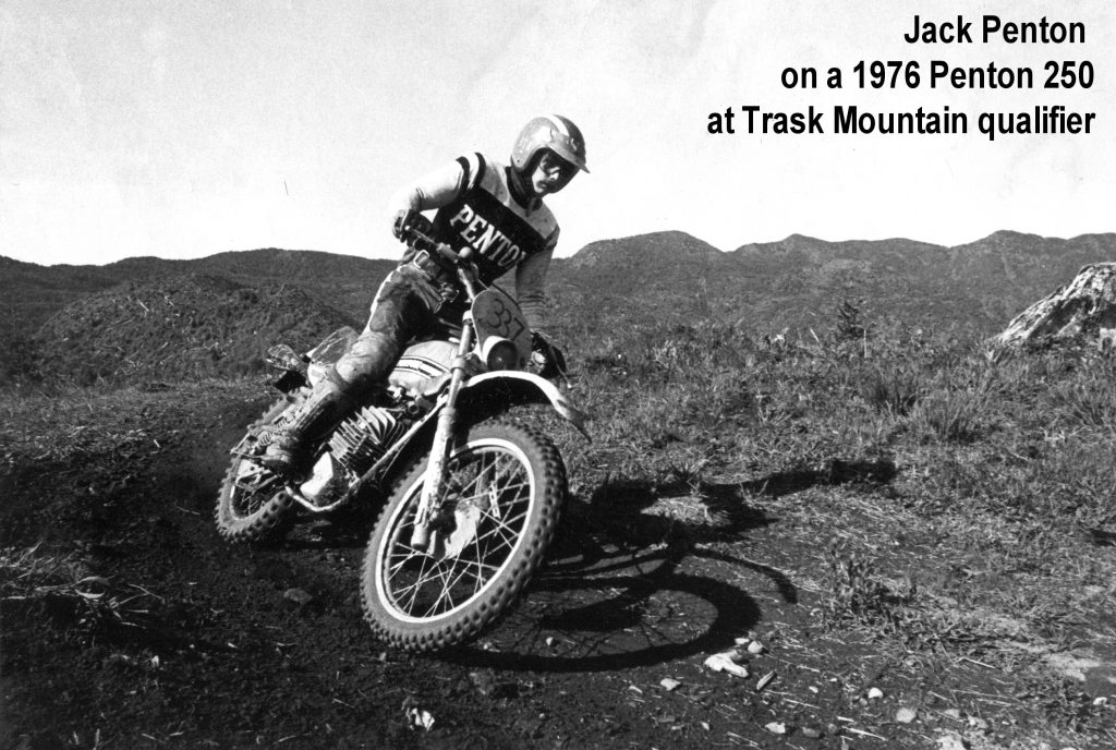 Motorcyclist racing on dirt track with mountains background.