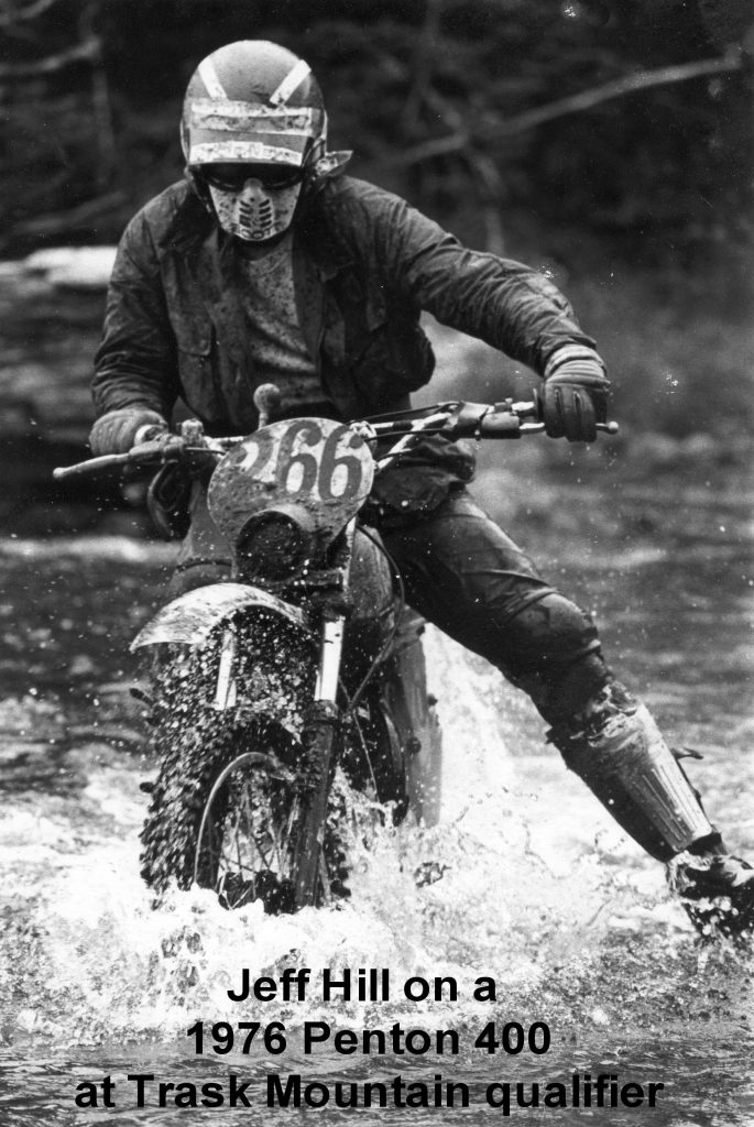 Motorcyclist riding through water obstacle in race