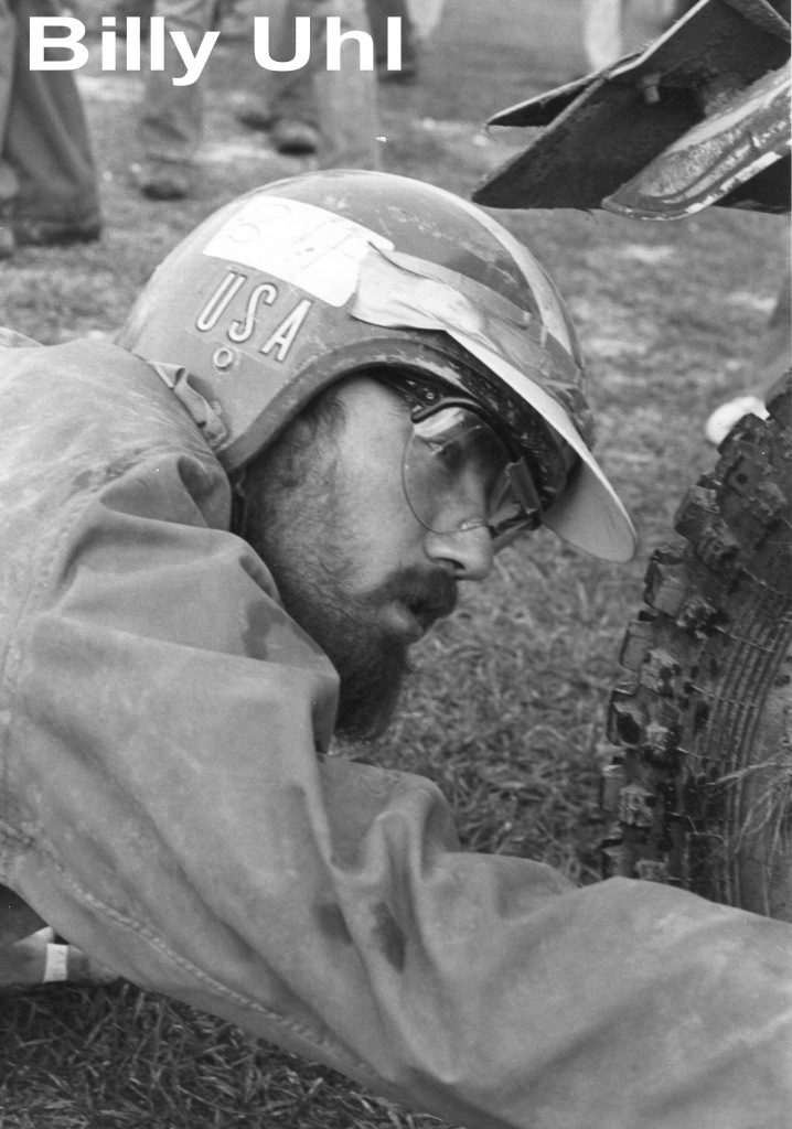 Person adjusting motorcycle wheel with helmet on.