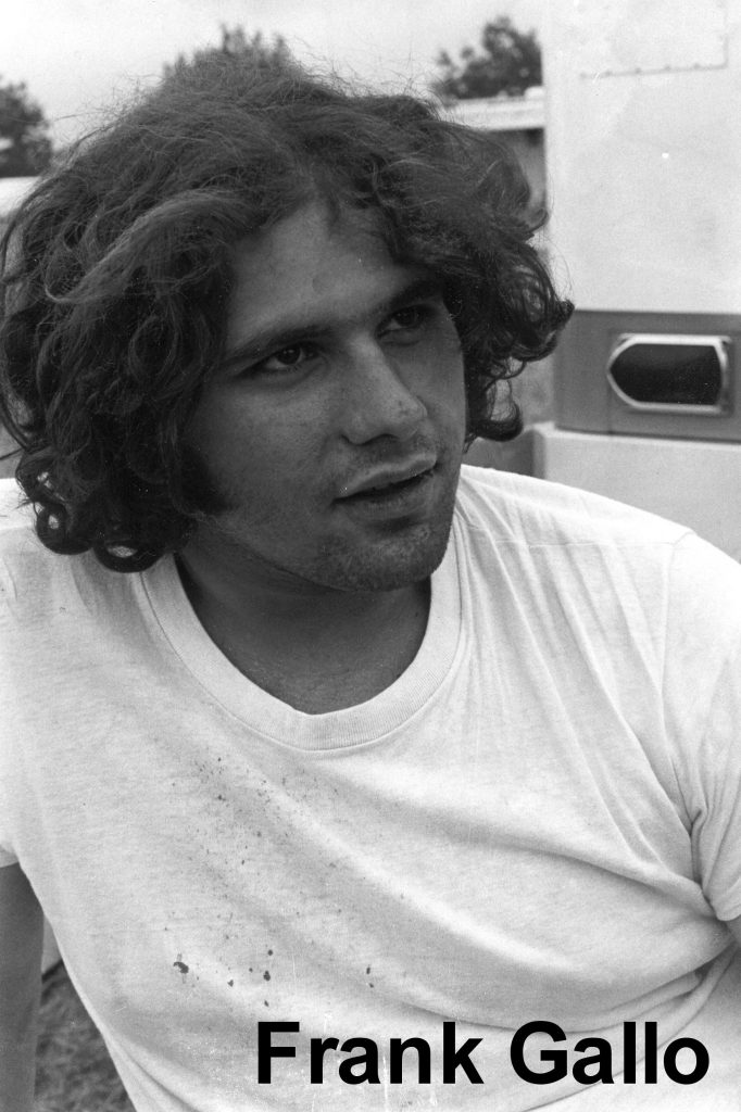 Man with curly hair wearing white shirt outdoors.