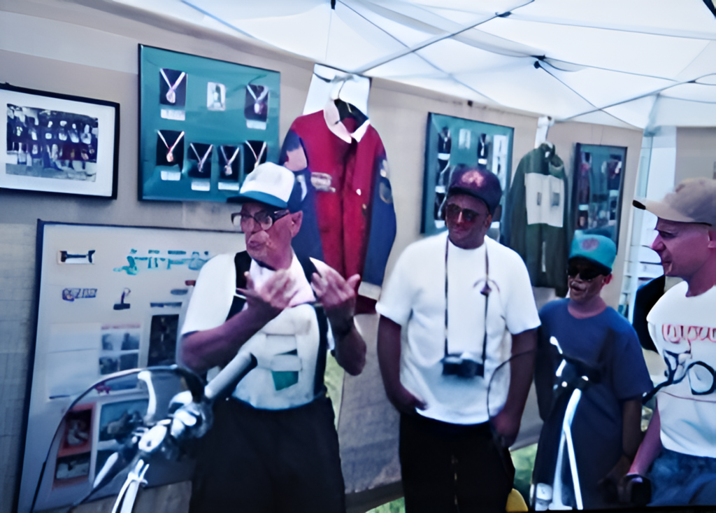 Group observes historical scooter exhibit under tent.