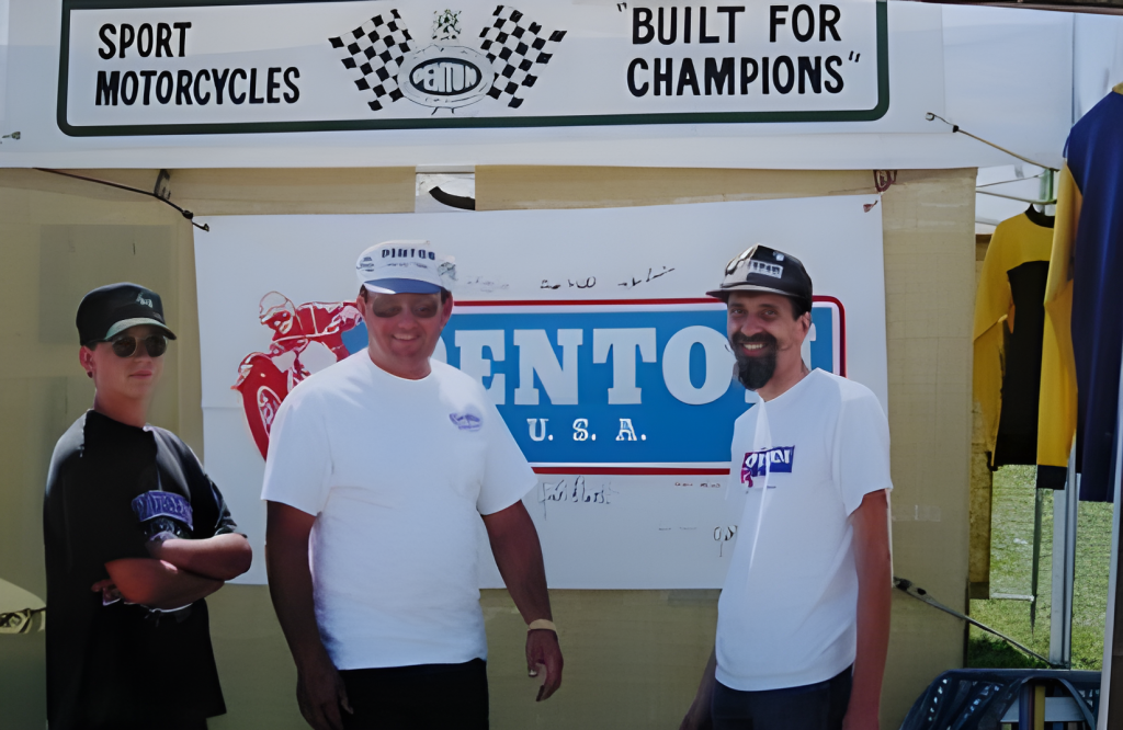 Men at motorcycle event, 'Built for Champions' sign.