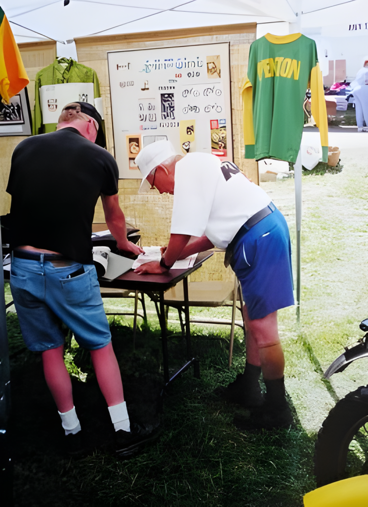 Two men writing at an outdoor booth