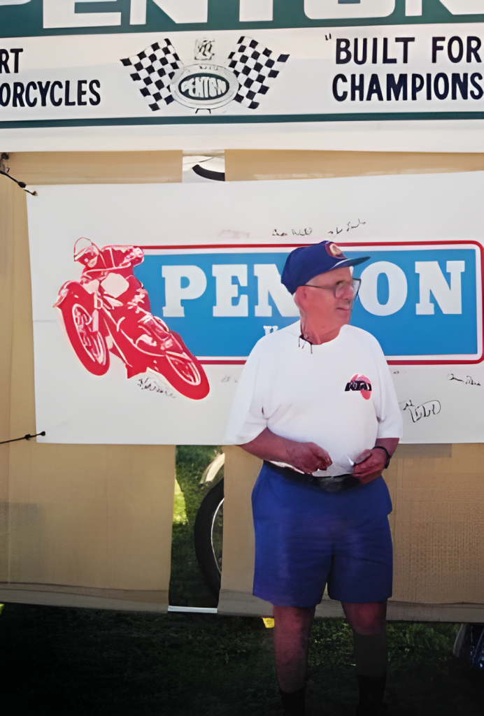 A man stands by a motorcycle sign.