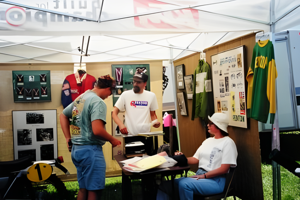 People at memorabilia booth with sports jerseys, medals.