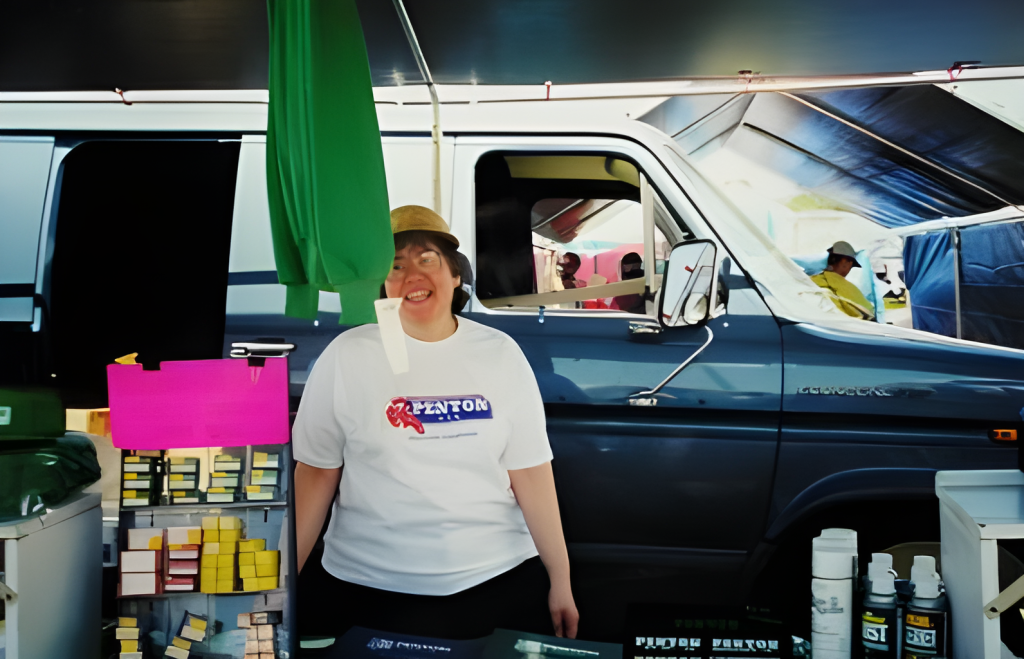 Smiling vendor at outdoor market booth.