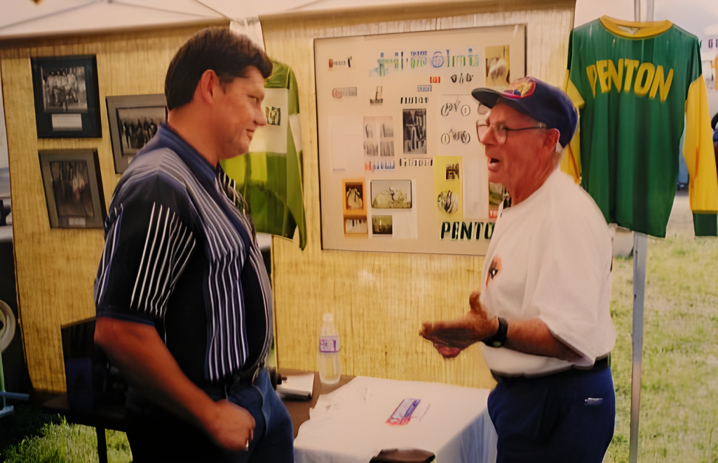 Two men talking at a vintage motorcycle event.