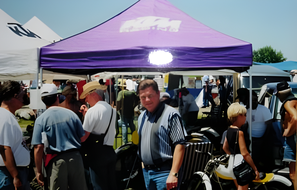 Crowd at outdoor event under purple tent.