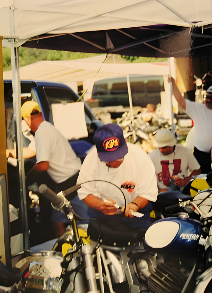 Men working on motorcycles under tent