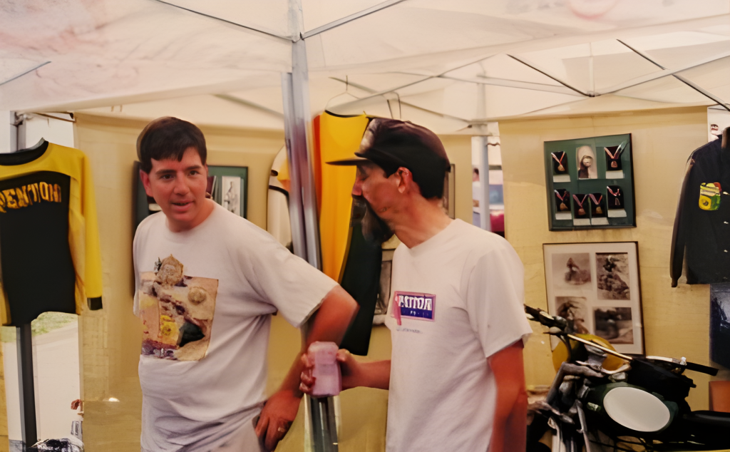 Two men talking at motocross exhibit booth.