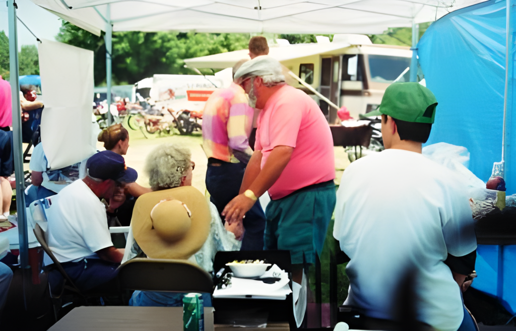 People gathering under a canopy at outdoor event.