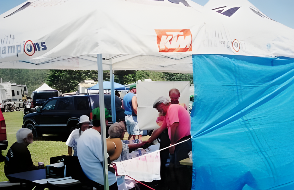 People gathered under tents at an outdoor event.