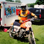Motocross rider with bike near trailer.