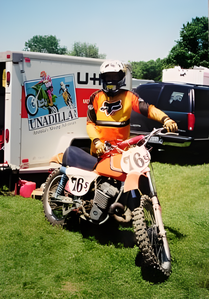 Motocross rider with bike near trailer.