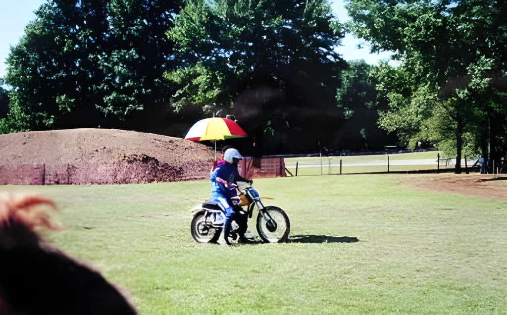 Rider on dirt bike near colorful umbrella outdoors.