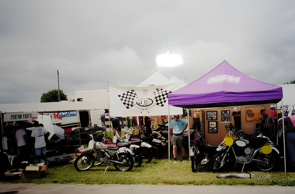 Outdoor flea market with motorcycles and tents.