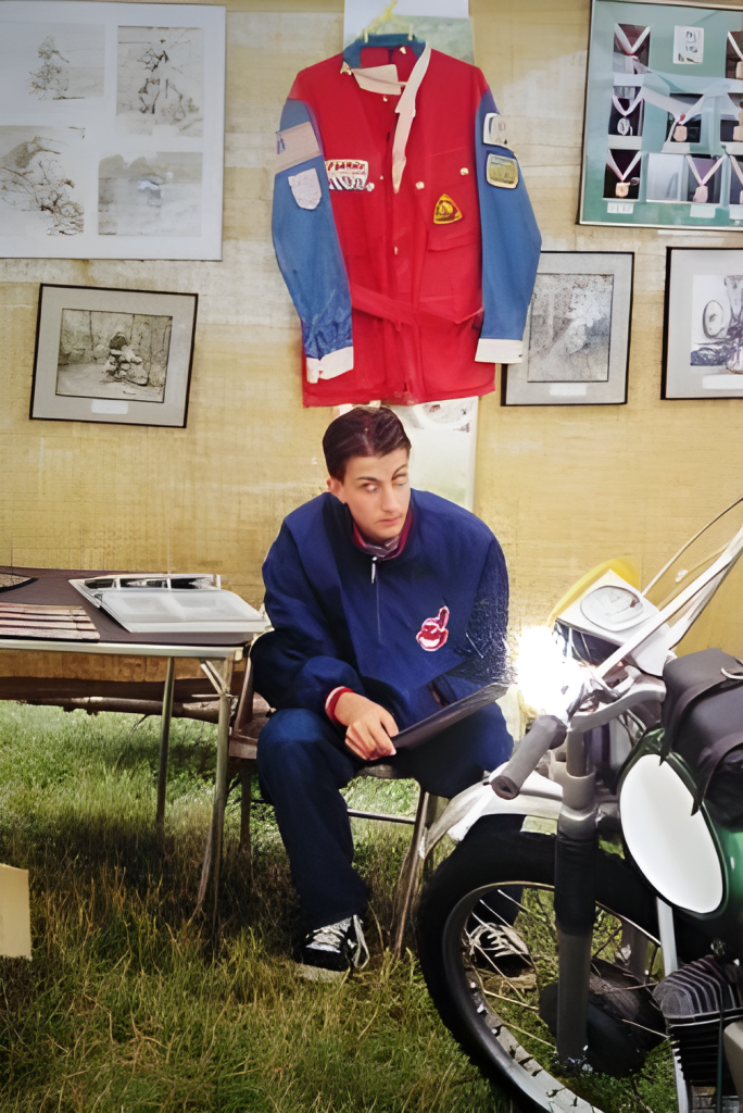 Man seated next to vintage motorcycle, photo display.