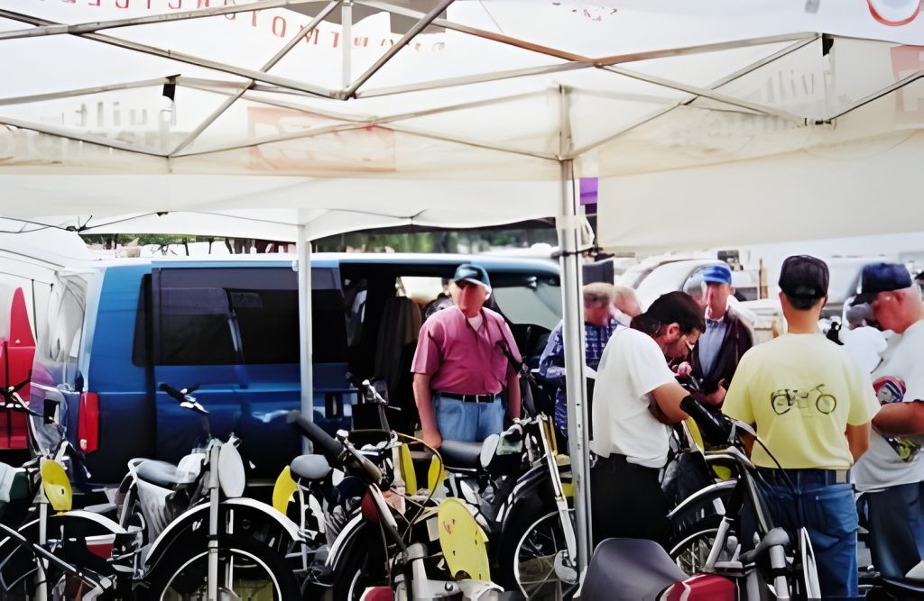People gathered around vintage motorcycles at outdoor event.