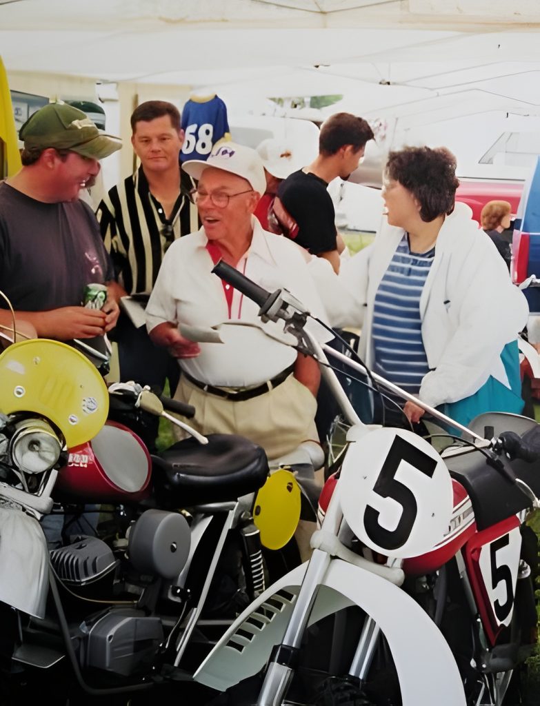 Group chatting near vintage motorcycles at an event.