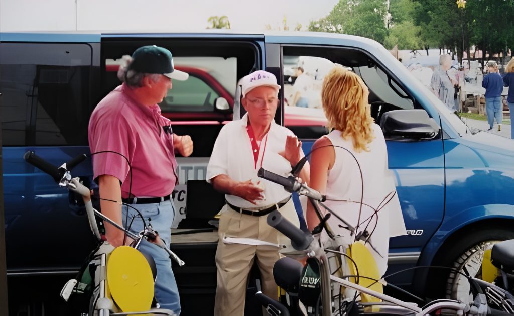 People conversing by van and parked bikes.