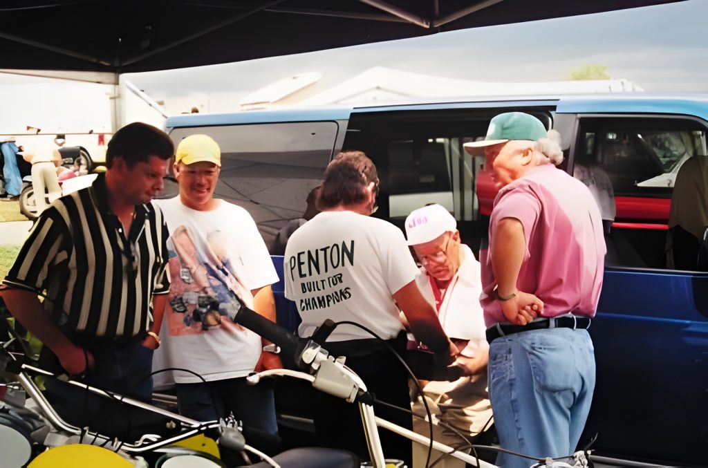 Group discussing motorcycles at outdoor event.