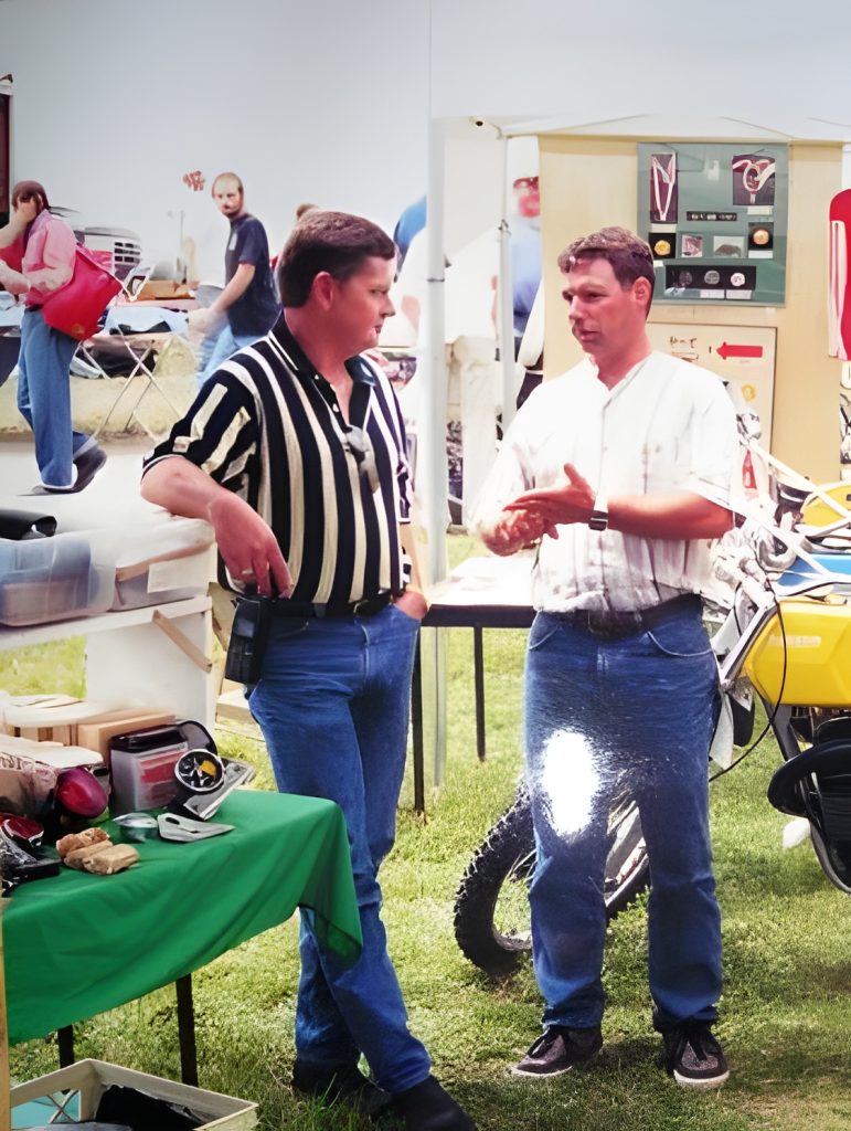 Two men talking at outdoor motorcycle event.