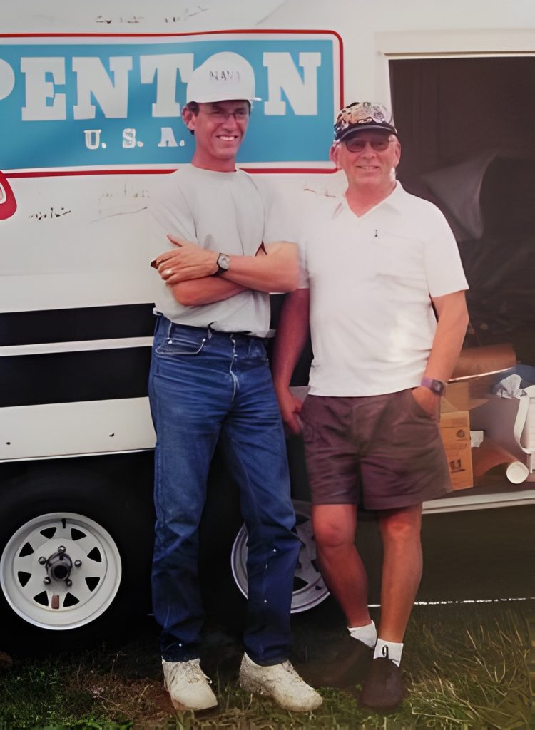 Two men smiling in front of trailer