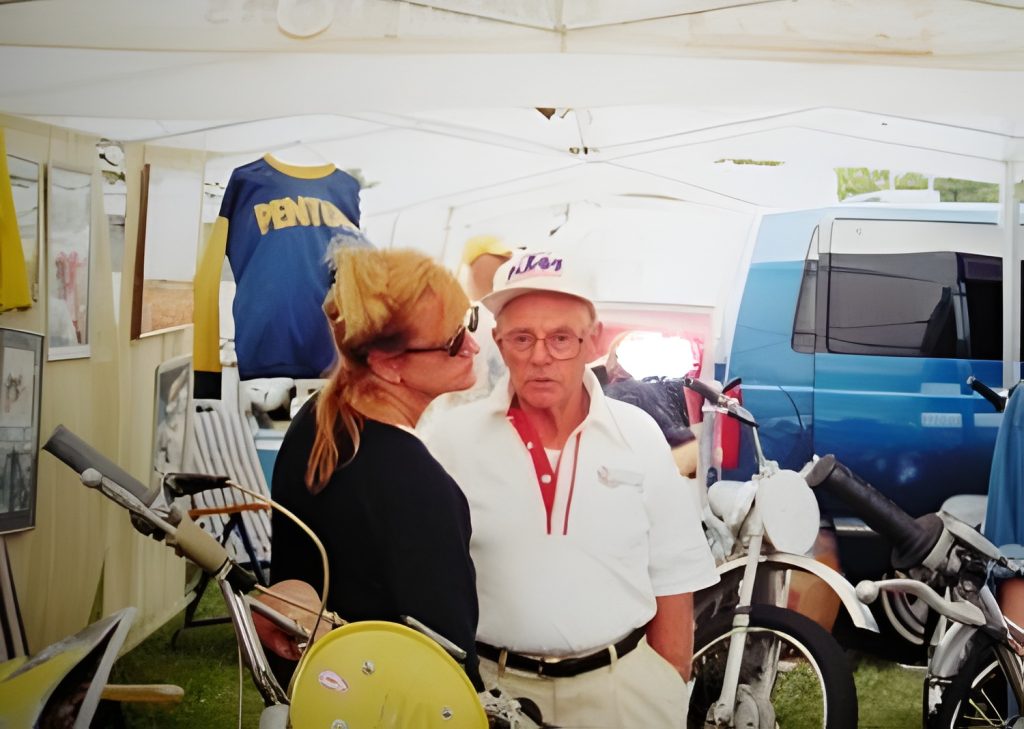 Vintage motorcycles at outdoor exhibit, two people conversing.