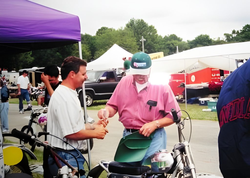 Men at outdoor motorcycle event exchanging handshake