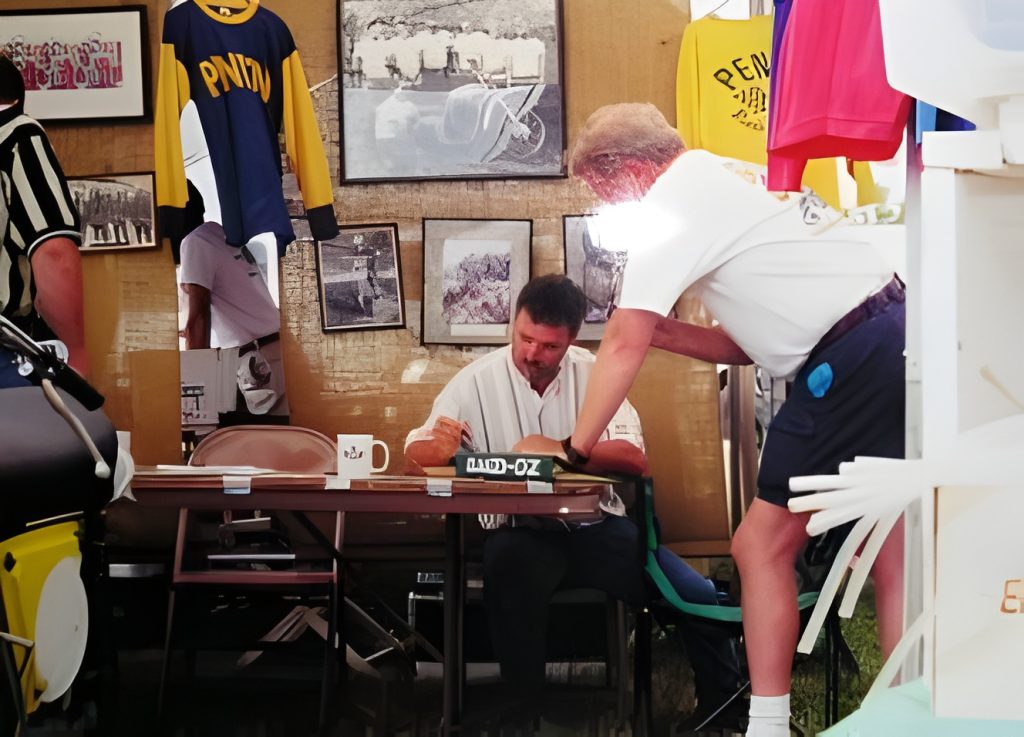 Man signing books at table display.