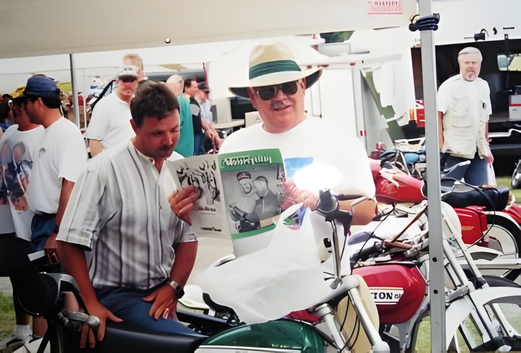 Men reading newspaper at motorcycle rally.