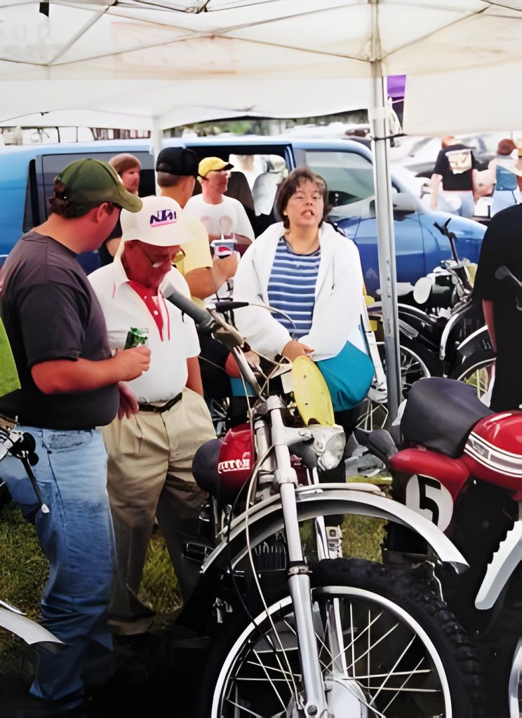 Group discussing vintage motorcycles at outdoor event