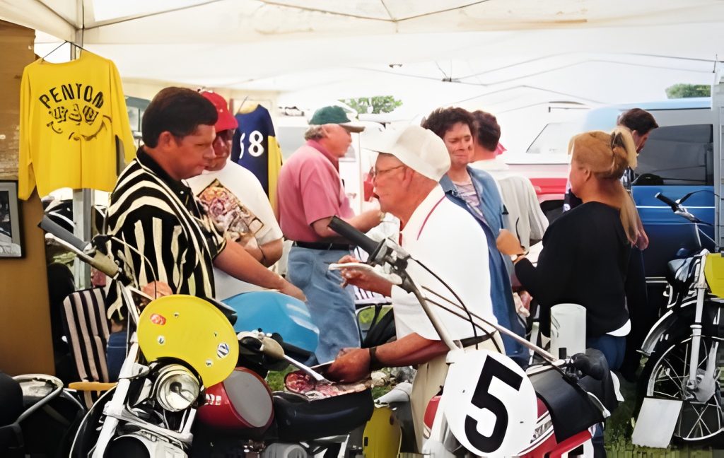 People gathered around vintage motorcycles and stalls.