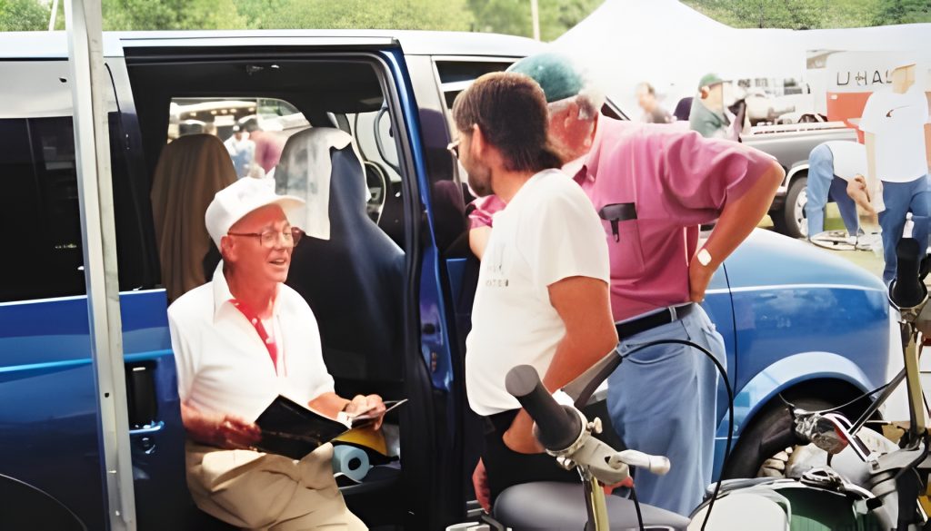 Group of men talking near a blue van.