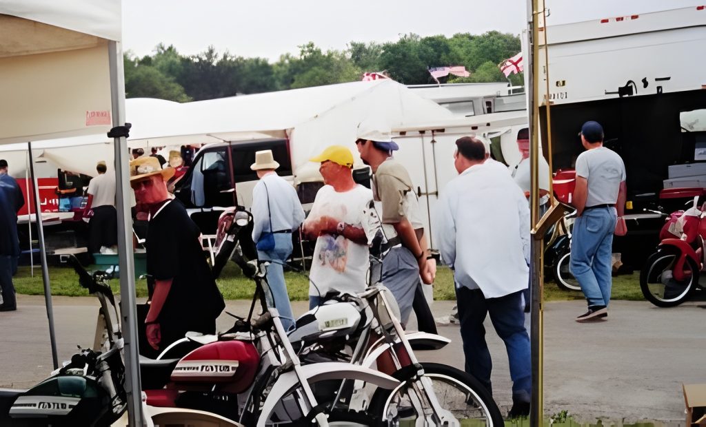 People at outdoor market with motorbikes.