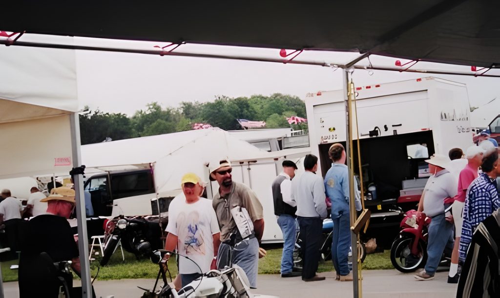 Crowd at outdoor event with tents and motorcycles.