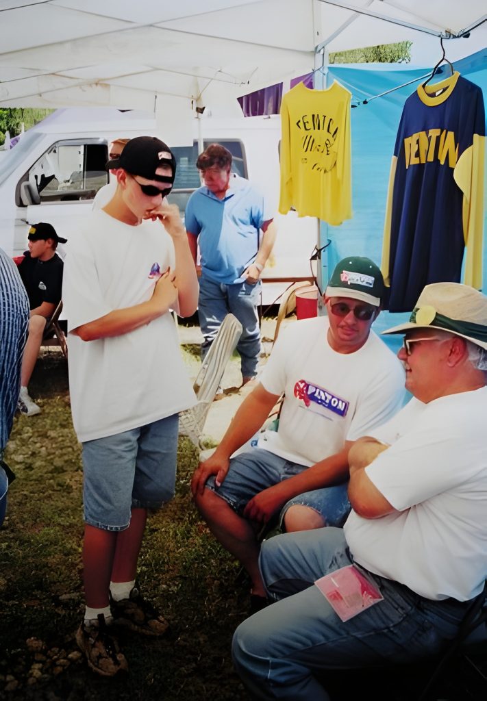 Group talking under tent with vintage shirts.
