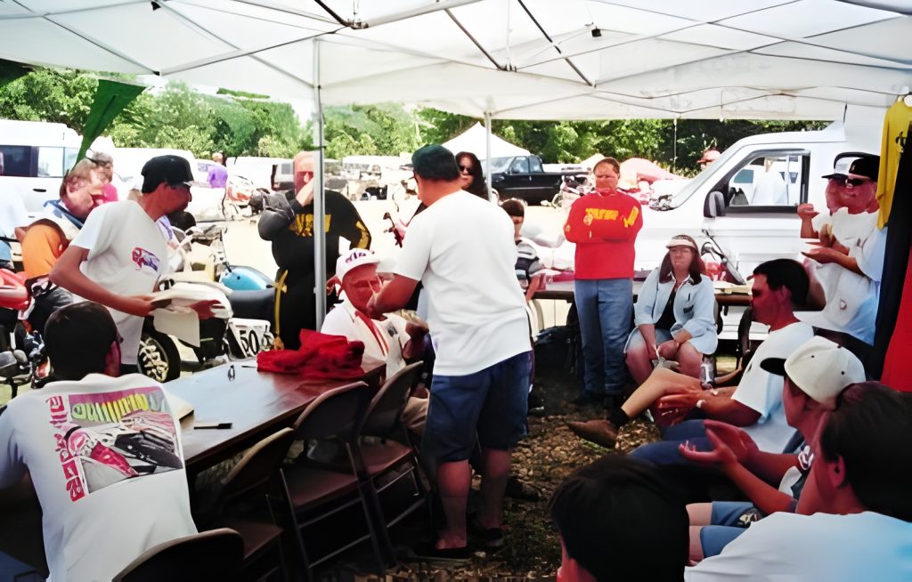People socializing at outdoor event under tent canopy.
