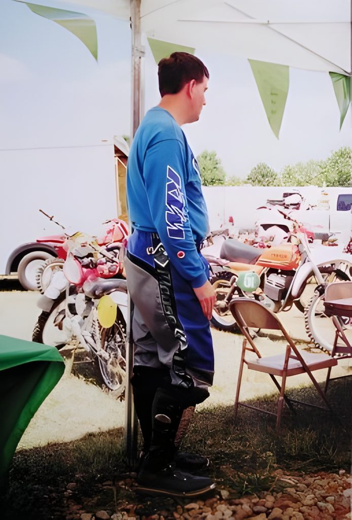 Person in motocross gear near parked motorcycles.