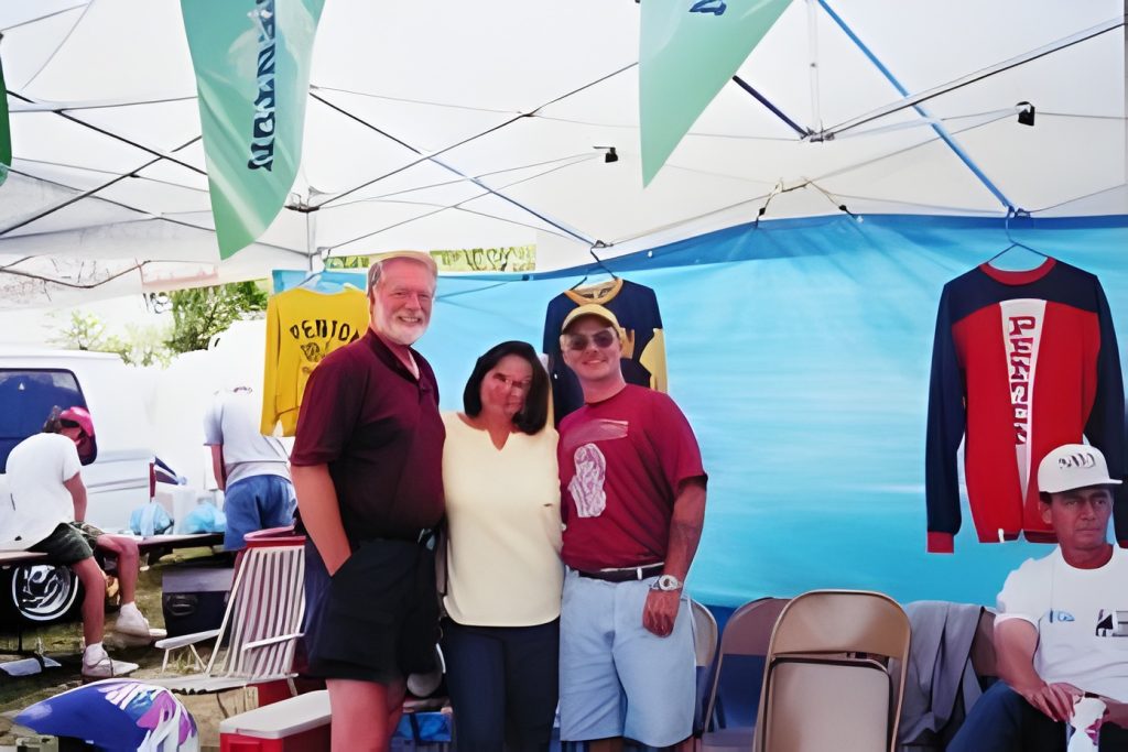 People under a tent with hanging shirts.