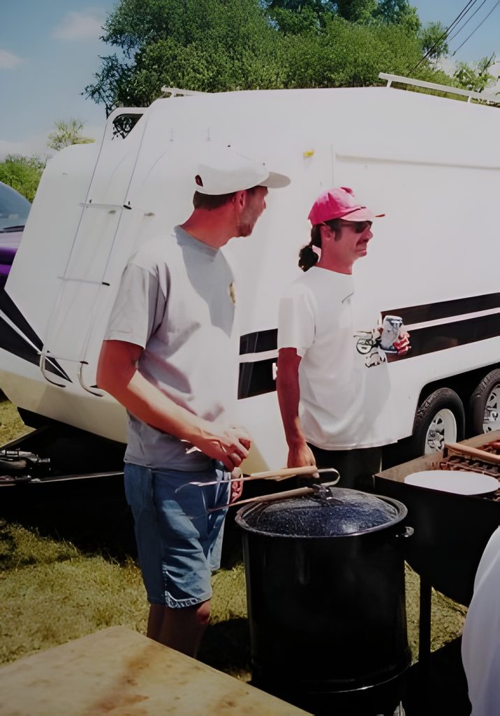Two men cooking outdoors near trailer