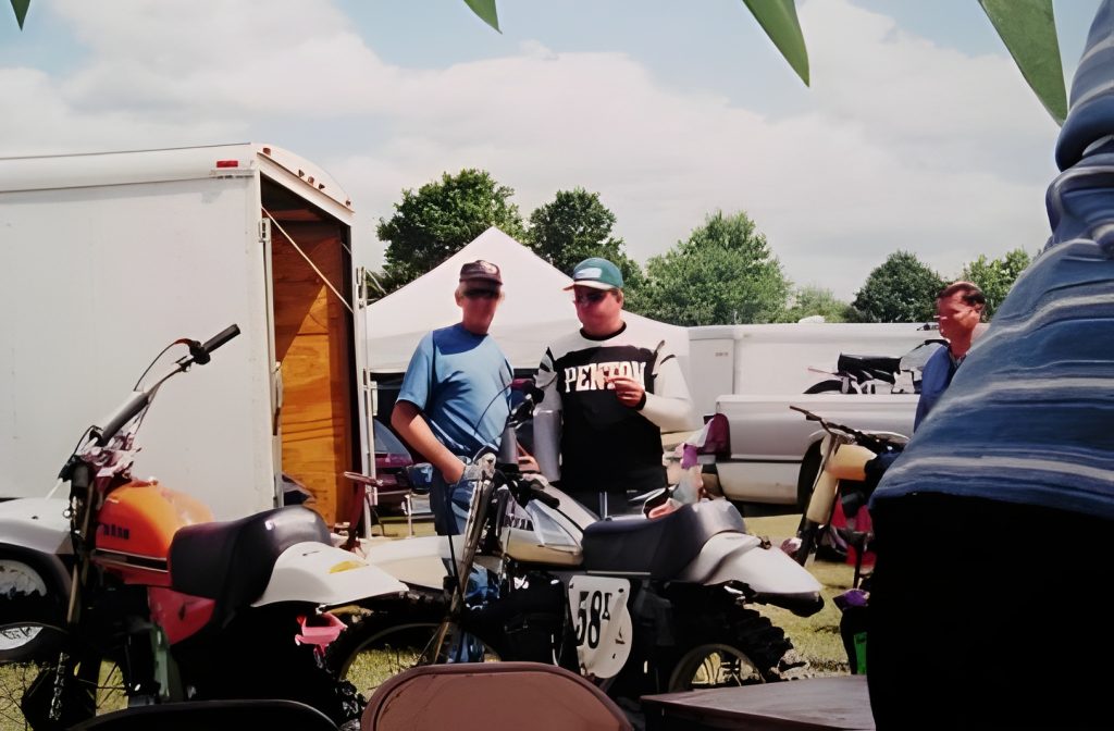 Two people near motorcycles at outdoor event.