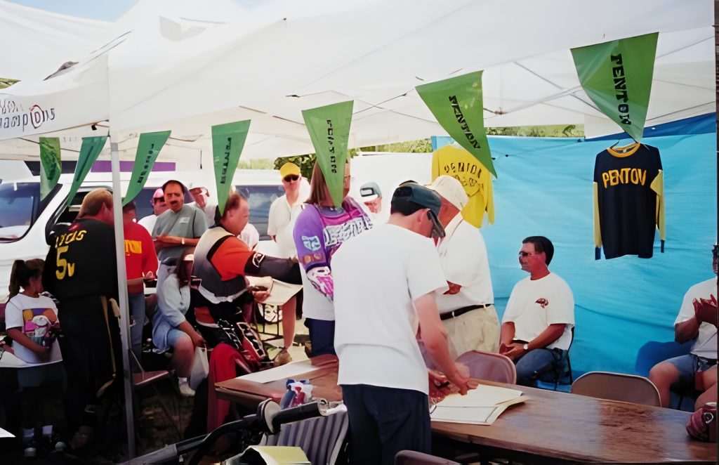 People gathering under tent with Penton jerseys displayed.