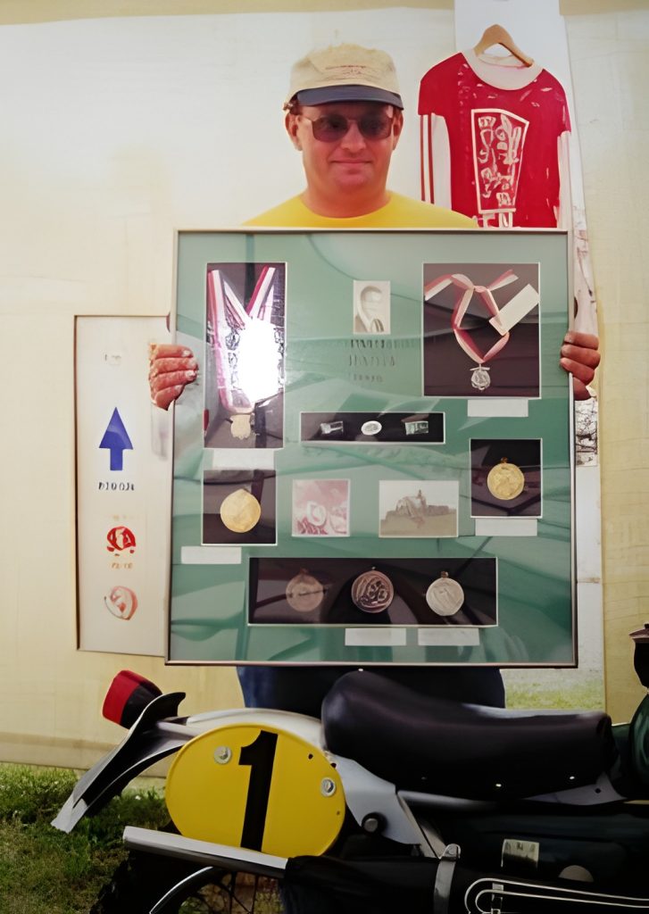 Person holding framed medals over motorcycle