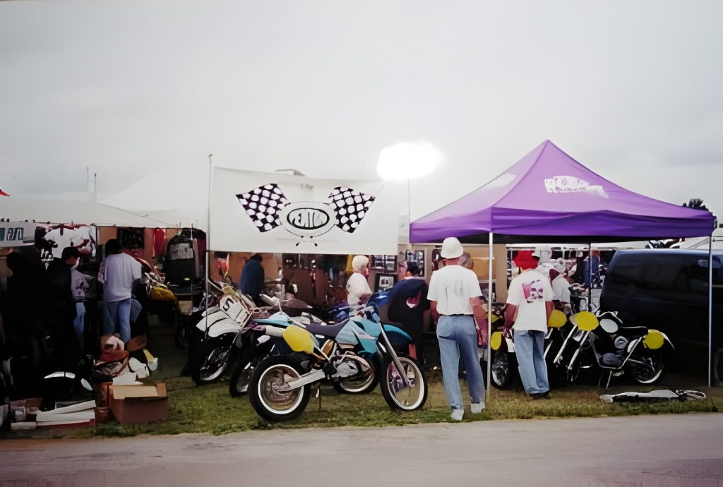 Outdoor motorcycle event with tents and people.