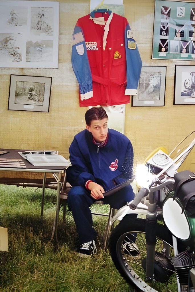 Man with motorcycle at outdoor display booth.