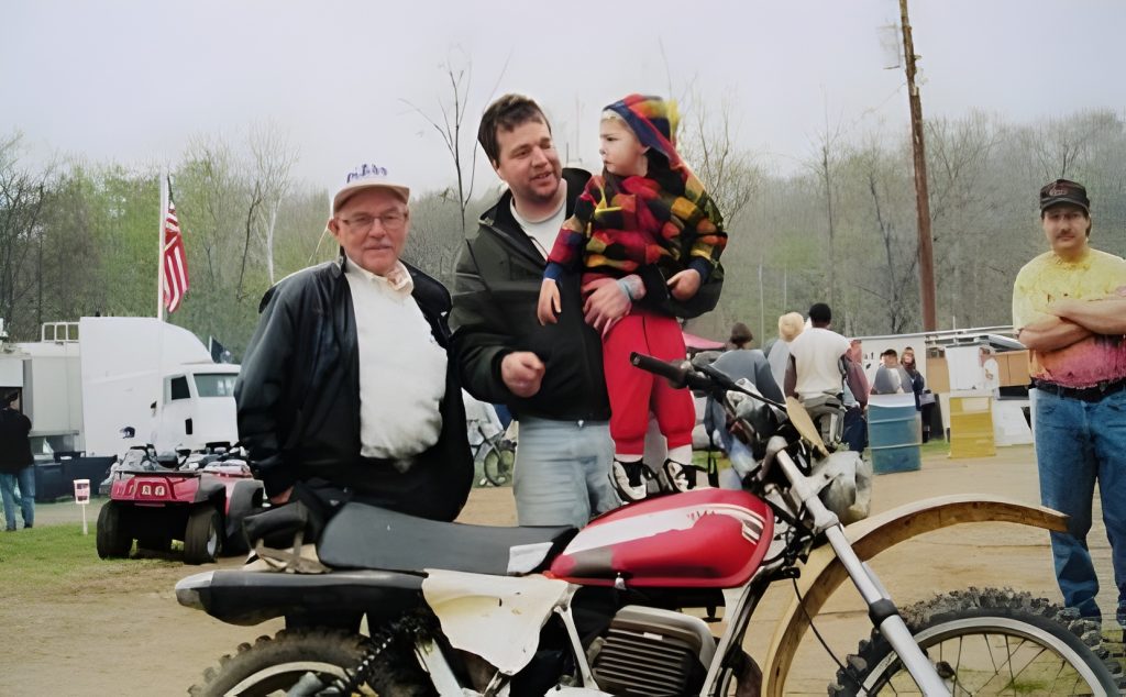 People gathered with motorcycle at outdoor event.