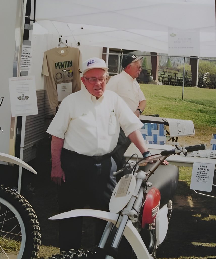 Man beside vintage motorcycle under tent display.
